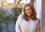 Older Hispanic woman standing outside and smiling