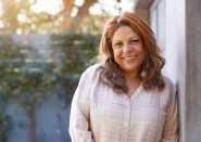 Older Hispanic woman standing outside and smiling